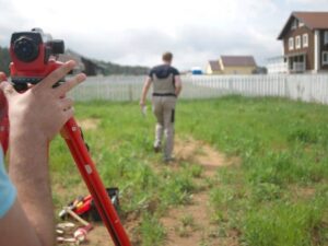 Surveyors locating residential property lines during a boundary survey that helps determine boundary survey cost